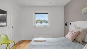 Un dormitorio con cama, ventana con vistas, radiador y una silla verde.