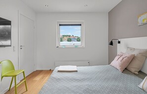 A bedroom with a bed, a window with a view, a radiator, and a green chair. - Amazing home in Ebeltoft with house sea view (Ebeltoft)