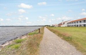A gravel path beside a body of water, leading to a building with a red roof. - Amazing home in Ebeltoft with house sea view (Ebeltoft)