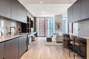 A modern kitchen with built-in appliances, a dining area with bar stools, and a large window offering a city view. - E11EVEN • 41ST FLOOR • ROOFTOP POOL • ZERO RESORT FEE (Miami)