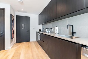 Eine moderne Küche mit dunklen Holzschränken, einer Edelstahl-Spüle und einem eingebauten Backofen.