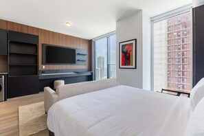 A modern hotel room with a large bed, a flat-screen TV mounted on the wall, a sofa, and a large window with a city view. - E11EVEN • 41ST FLOOR • ROOFTOP POOL • ZERO RESORT FEE (Miami)