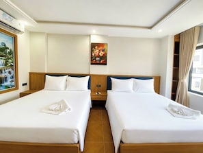 A hotel room with two beds, a painting on the wall, and a window with curtains. - Uniland Ninh Bình Hotel (Ninh Binh)
