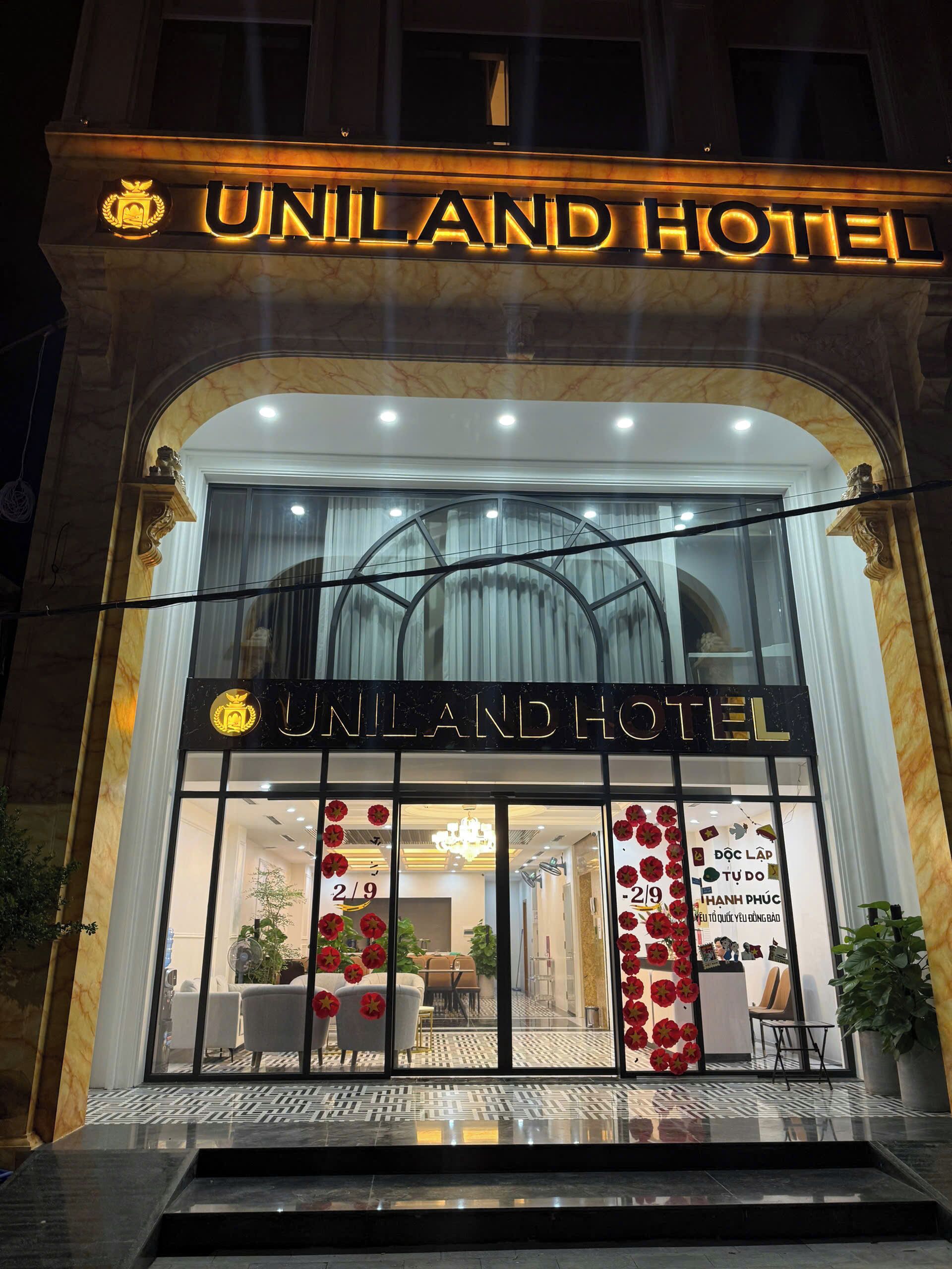 Exterior del HOTEL UNILAND con un letrero llamativo, grandes ventanales y una entrada moderna.