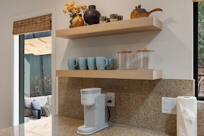 A kitchen with a coffee maker, a tea pot, and a shelf with cups and vases. - West Sedona retreat with 4 bedrooms, hot tub, and Red Rock views. (Sedona)