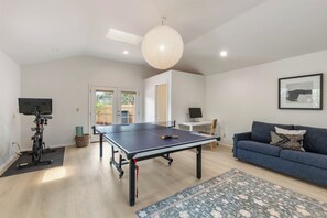 A living room with a ping pong table, a blue sofa, a framed picture on the wall, and a ceiling fan. - West Sedona retreat with 4 bedrooms, hot tub, and Red Rock views. (Sedona)