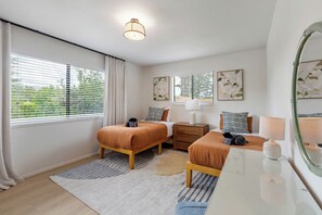 A modern bedroom with two beds, a nightstand, a dresser, a mirror, and artwork on the walls. - West Sedona retreat with 4 bedrooms, hot tub, and Red Rock views. (Sedona)