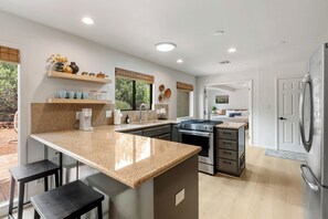 Uma cozinha moderna com bancadas de granito, eletrodomésticos de aço inoxidável e um balcão de refeições rápidas.