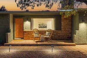 A building with a brick exterior, a wooden door, and two wicker chairs outside. - West Sedona retreat with 4 bedrooms, hot tub, and Red Rock views. (Sedona)
