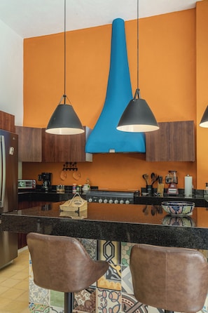 A modern kitchen with a central island, pendant lights, and a stove. - Colonial House in Downtown  (Mérida)