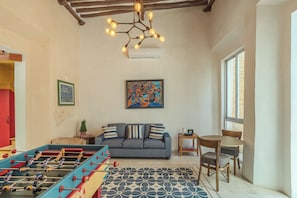 A living room with a sofa, a foosball table, a painting, and a window. - Colonial House in Downtown  (Mérida)