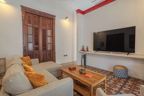 A living room with a sofa, a coffee table, a television on a stand, and a patterned floor. - Colonial House in Downtown  (Mérida)