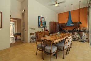 A spacious dining area with a wooden table and chairs, a kitchen with modern appliances, and a ceiling fan. - Colonial House in Downtown  (Mérida)