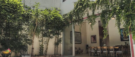 A modern building with a swimming pool, outdoor seating, and greenery.