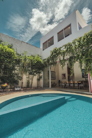 A modern building with a swimming pool, outdoor seating, and greenery. - Colonial House in Downtown  (Mérida)