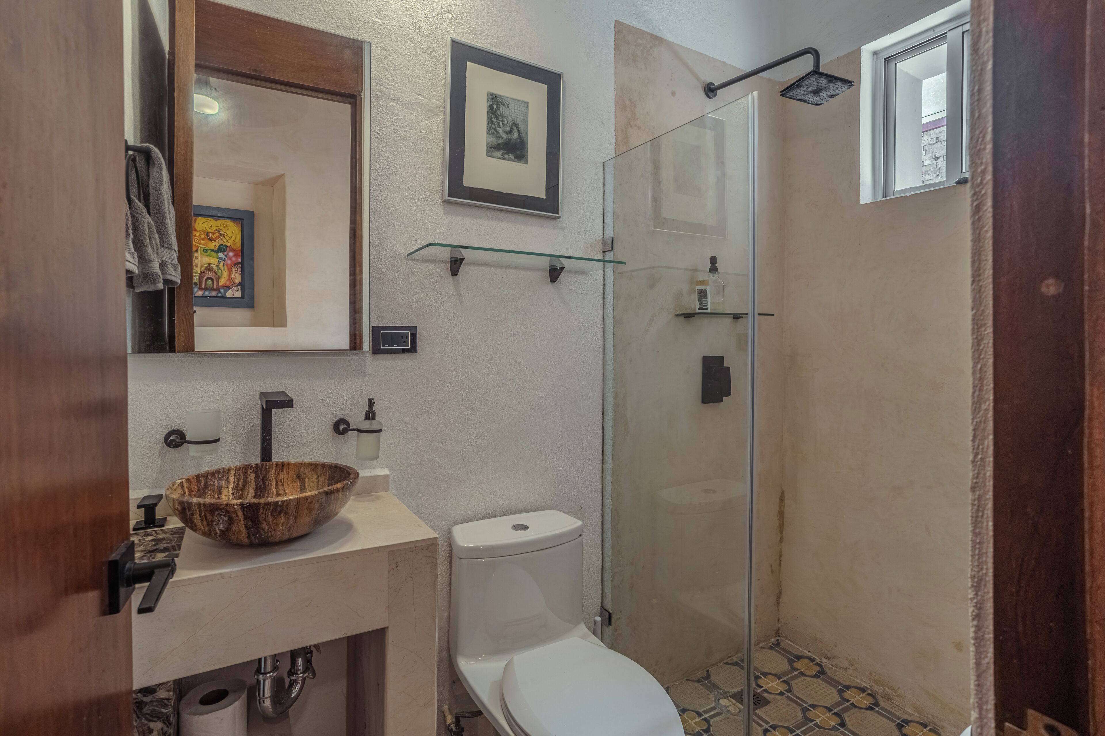 Ein Badezimmer mit einem Waschbecken aus Holz, einer Toilette und einer Duschkabine aus Glas.