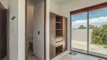 Una habitación con un amplio ventanal corredera que da a un espacio exterior, una estantería empotrada de madera y un suelo de baldosas estampadas.