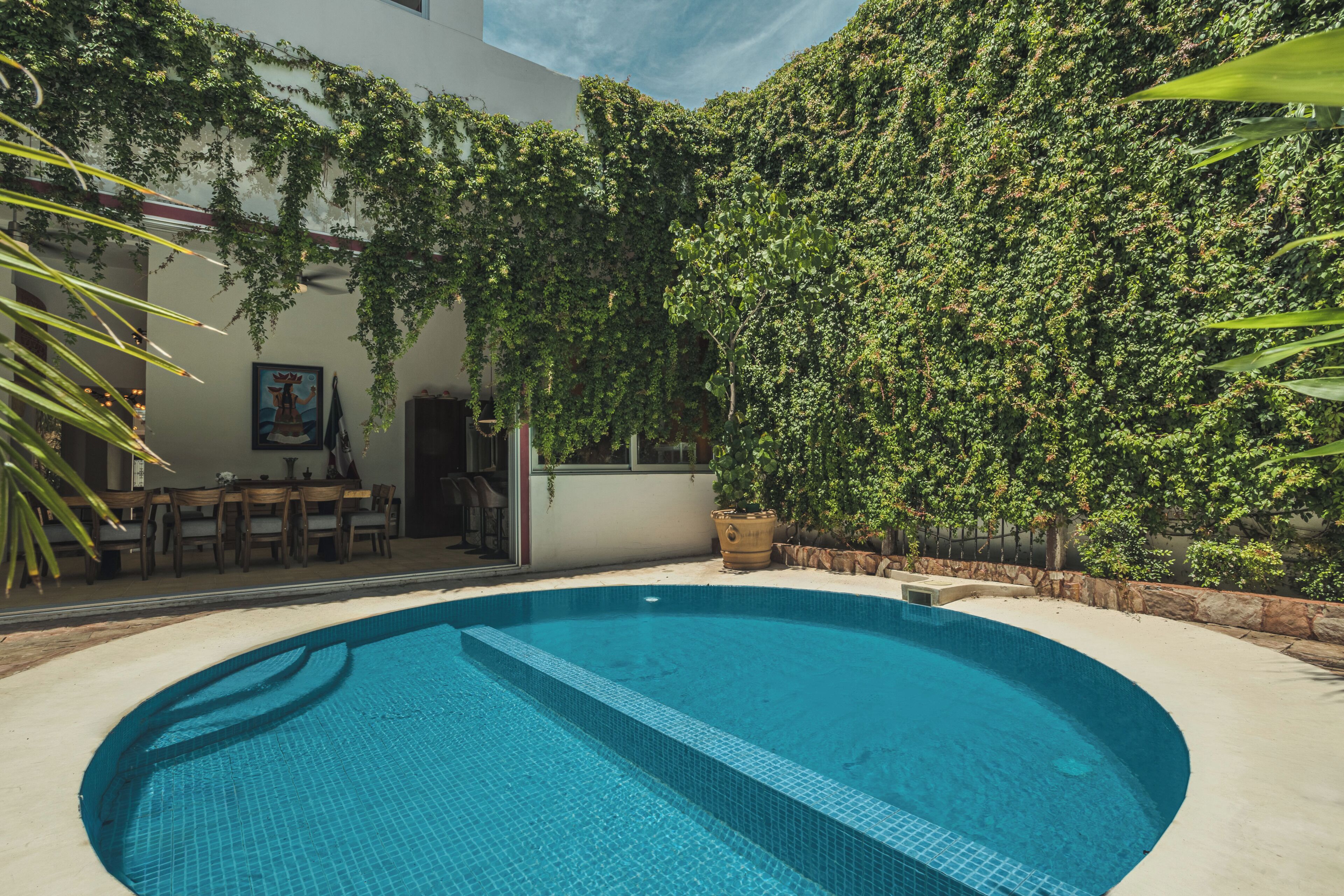 A swimming pool with a tiled edge, surrounded by a patio area with outdoor furniture.