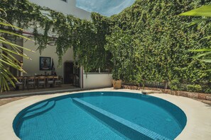 Una piscina con borde de azulejos, rodeada por una zona de patio con muebles de exterior.