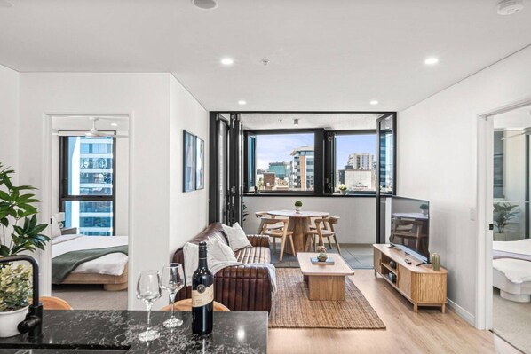 En moderne lejlighed med opholdsstue, spiseplads og en balkon med udsigt over byen.