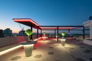 An outdoor rooftop terrace with a red canopy, hexagonal tiles, and potted plants. - Luxury Meets Lifestyle (Fortitude Valley)