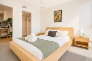 Et hotelværelse med en seng, et natbord, et billede på væggen og en dør til et badeværelse.