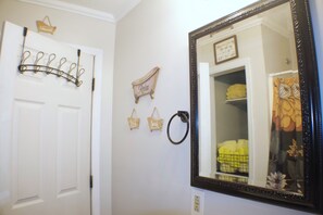 A bathroom with a white door, a mirror with a decorative frame, and wall-mounted towel racks. - Spacious 4-bedroom house in charming Ringgold with big yard and pet friendly. (Ringgold)