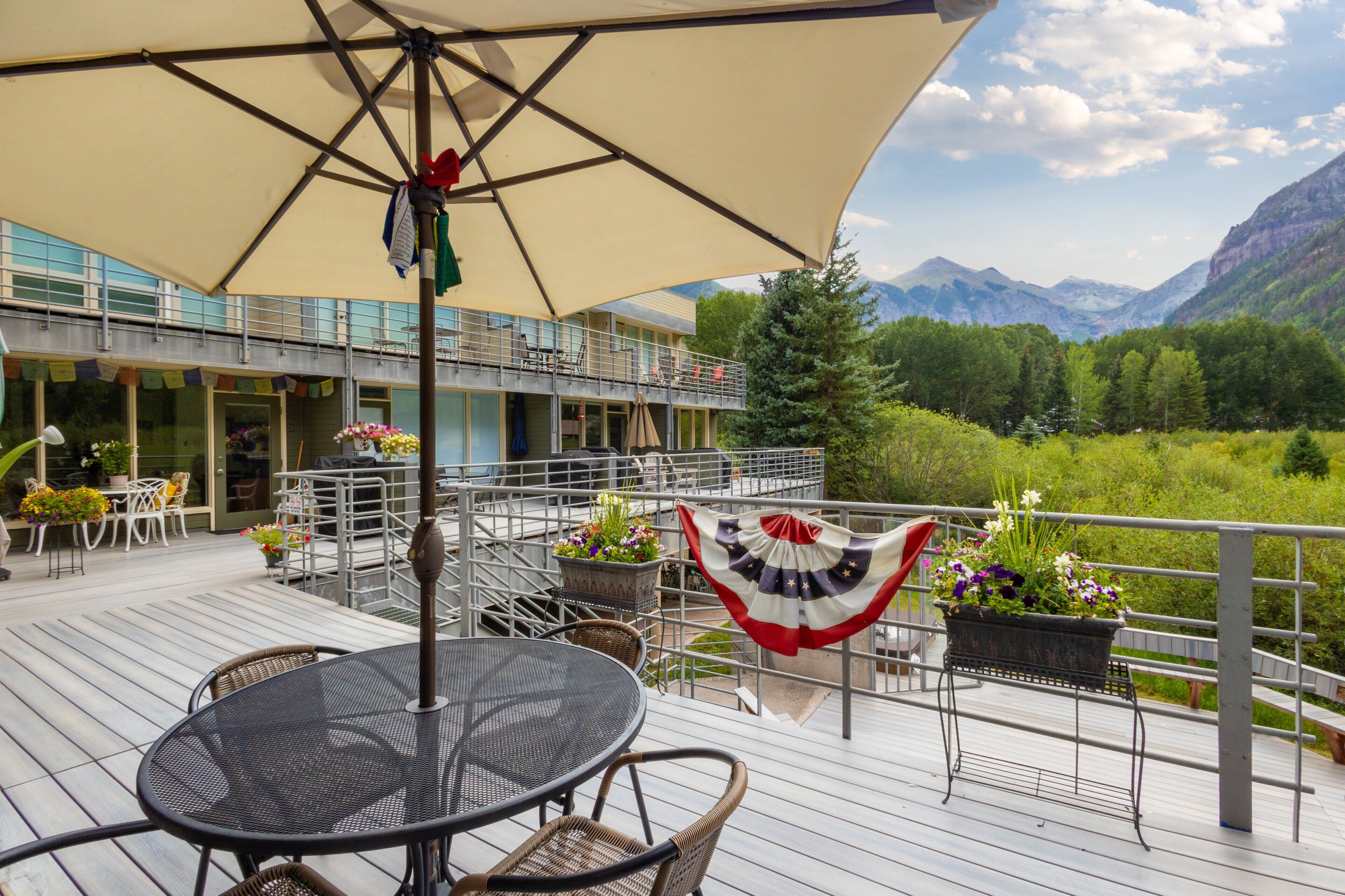 A deck with outdoor seating, a flag, and a mountain view.