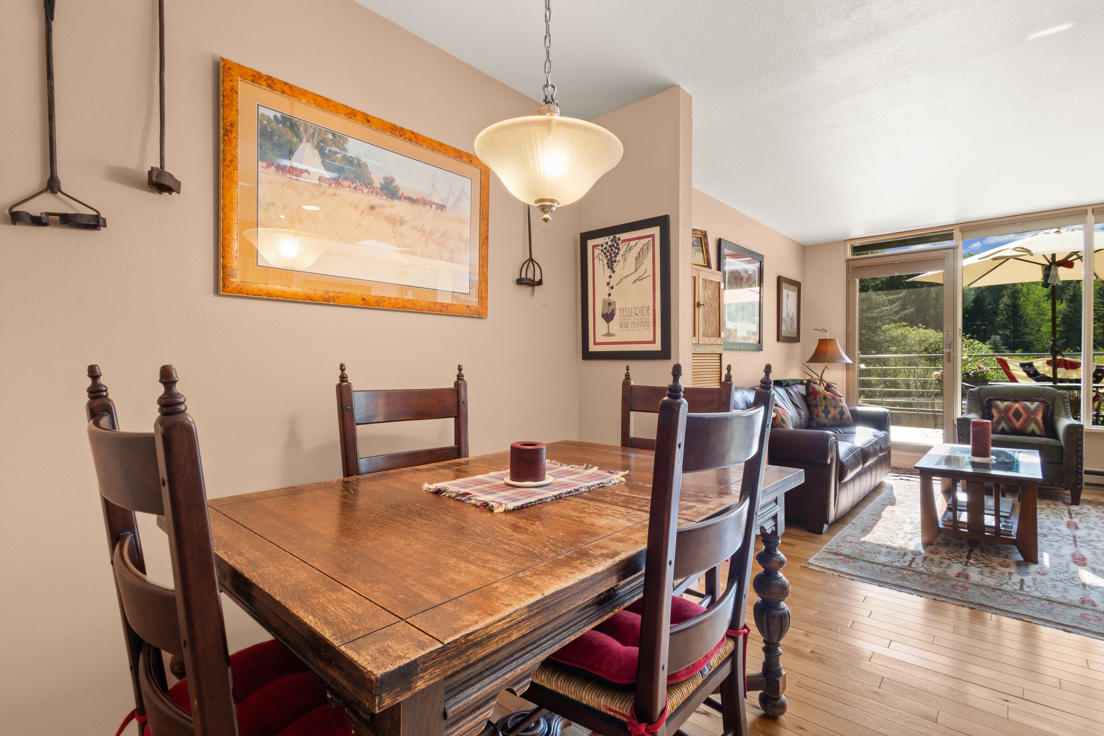 A dining area with a wooden table, chairs, and a hanging light fixture.