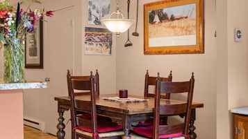 Un comedor con una mesa y sillas de madera, un florero con flores y obras de arte en las paredes.