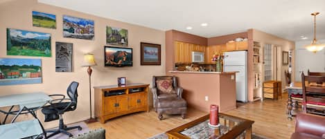 A spacious living area with a dining table, comfortable seating, and a kitchen in the background.