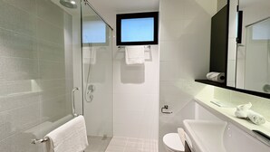 A modern bathroom with a glass-enclosed shower, a toilet, a sink with a mirror, and a towel rack. - Moulmein Studios by K&C Serviced Apartment (Singapore)