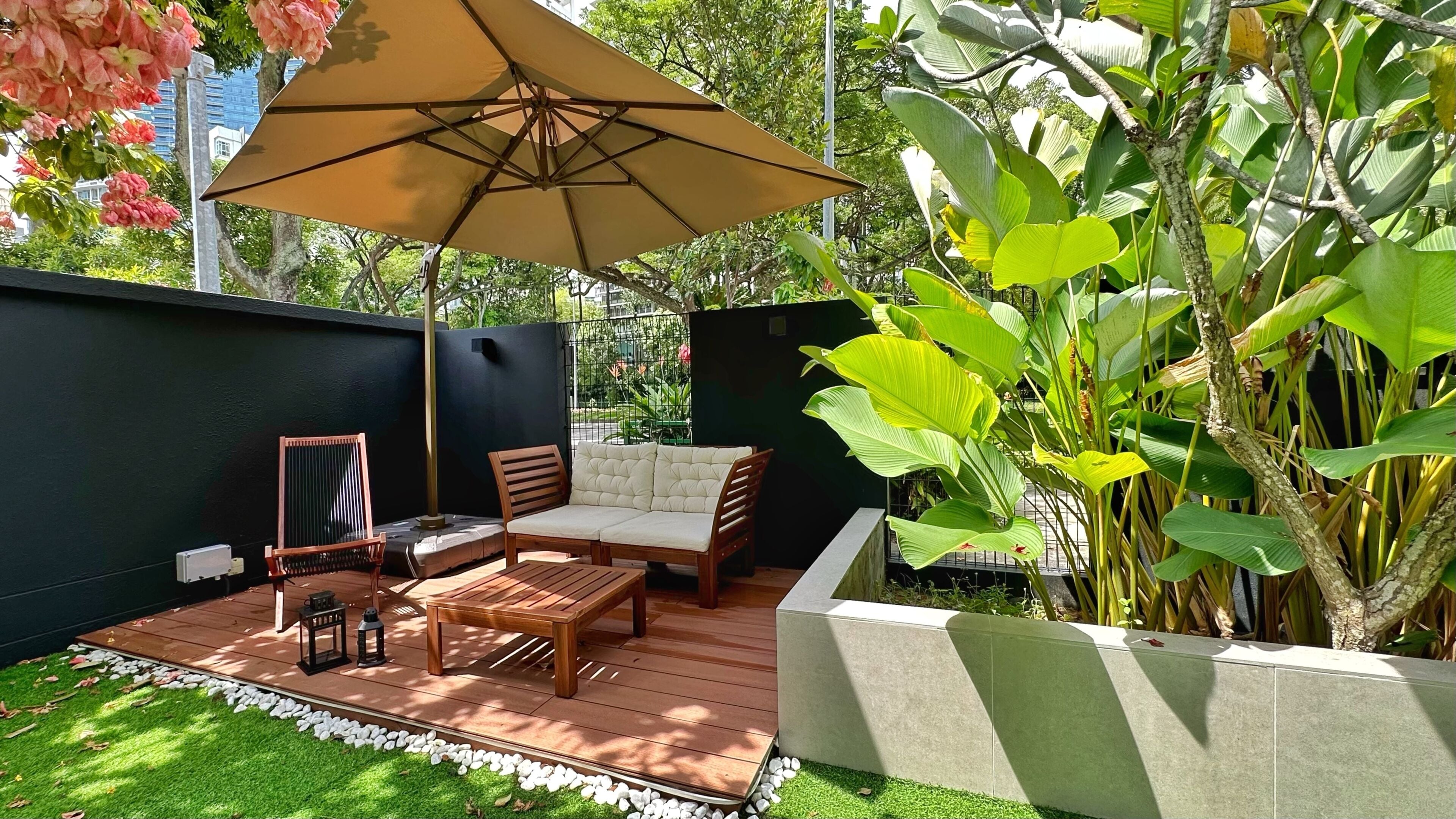 Un patio con una mesa de madera, dos sillas, un banco y un paraguas grande.