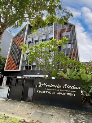 Un edificio moderno con un cartel que indica 'Moulmein Studios K&C Serviced Apartment' en el número 147 de Moulmein Road, Singapur.