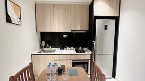 A compact kitchen with a refrigerator, sink, and a dining table with chairs.