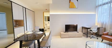 Una sala moderna con comedor, televisor de pantalla plana y sofá.