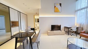 A modern living room with a dining area, a flat-screen TV, and a sofa.