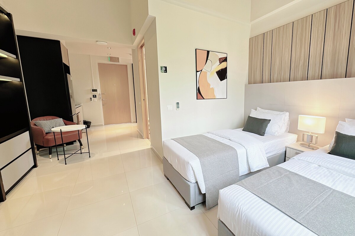 Habitación de hotel con dos camas, un escritorio, una silla, un televisor y un cuadro en la pared.