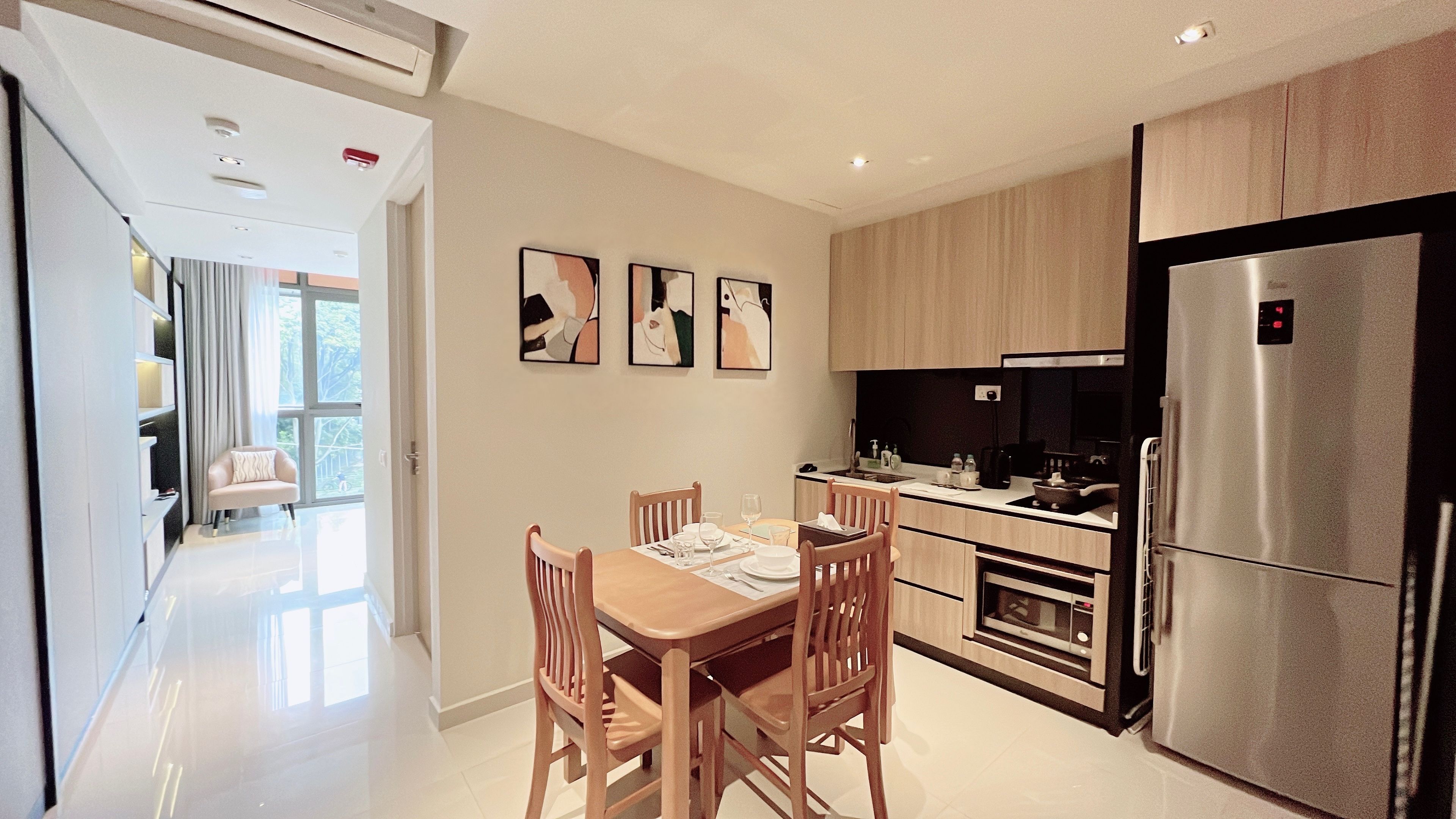 A modern kitchen with a dining area, stainless steel appliances, and artwork on the wall.