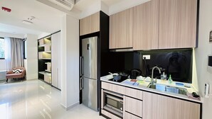 A modern kitchen with built-in appliances, a dining area with a chair, and a view of the outdoors. - Moulmein Studios by K&C Serviced Apartment (Singapore)