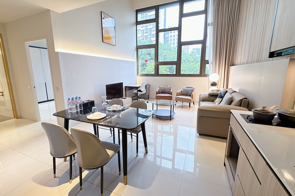 Una habitación de hotel moderna con comedor, sofá, televisor y espacio para la cocina.