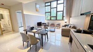 A modern hotel room with a dining area, a sofa, a TV, and a kitchen area. - Moulmein Studios by K&C Serviced Apartment (Singapore)