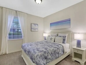 A bedroom with a bed, two bedside lamps, a window with curtains, and a painting on the wall. - Coastal Paradise Near the Beach - Private Heated Pool - 4BR Marco Island Retreat (Marco Island)
