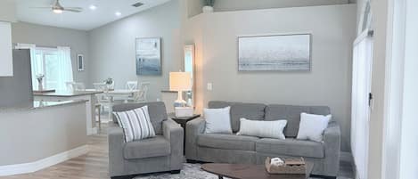 Ein modernes Wohnzimmer mit einem grauen Sofa, einem Couchtisch und einem gemusterten Teppich.