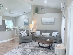Ein modernes Wohnzimmer mit einem grauen Sofa, einem Couchtisch und einem gemusterten Teppich.