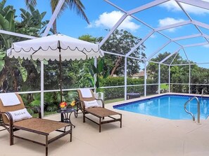 A poolside area with two lounge chairs, a canopy, and a view of a swimming pool. - Coastal Paradise Near the Beach - Private Heated Pool - 4BR Marco Island Retreat (Marco Island)