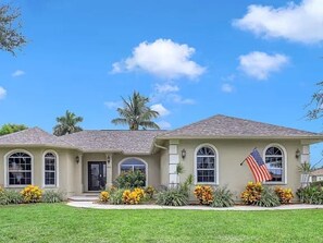 A two-story house with a front porch, a flag, and a well-maintained lawn. - Coastal Paradise Near the Beach - Private Heated Pool - 4BR Marco Island Retreat (Marco Island)
