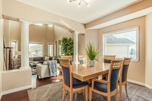 A dining area with a wooden table and chairs, a potted plant, and a view of the backyard. - Million Dollar Home In Lewis Estaes Golf Course By Henday/Whitemud with Garage! (Edmonton)