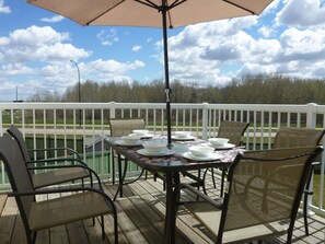 A deck with a table set for four, surrounded by wicker chairs, under a large umbrella. - Million Dollar Home In Lewis Estaes Golf Course By Henday/Whitemud with Garage! (Edmonton)