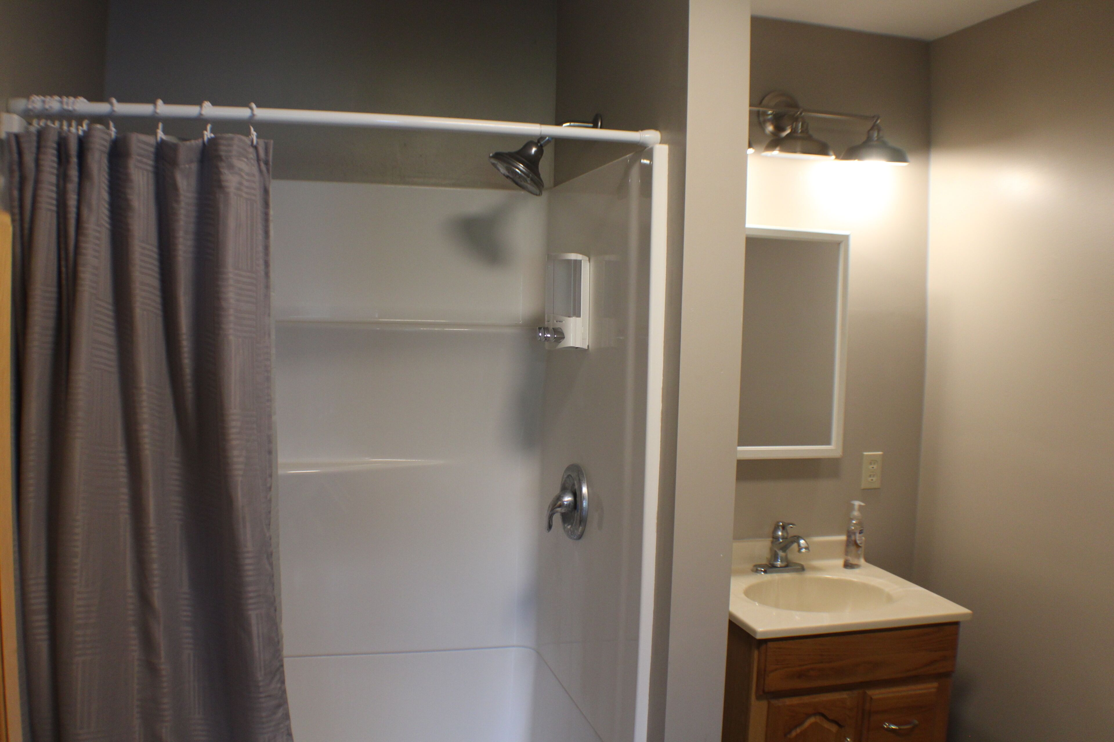 Une salle de bain avec une douche, un lavabo et un miroir.